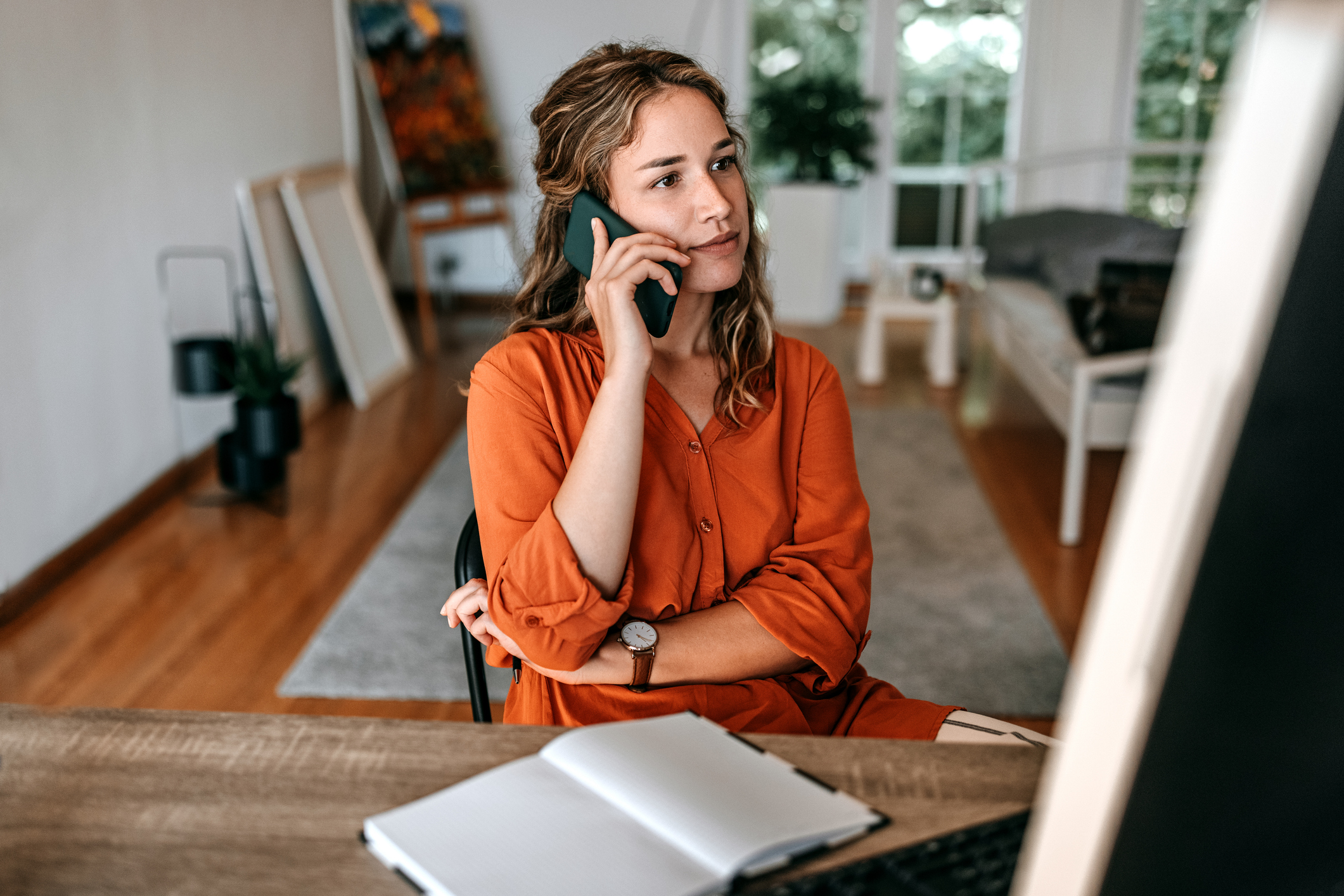 Junge Frau, die im Homeoffice auf dem Smartphone spricht