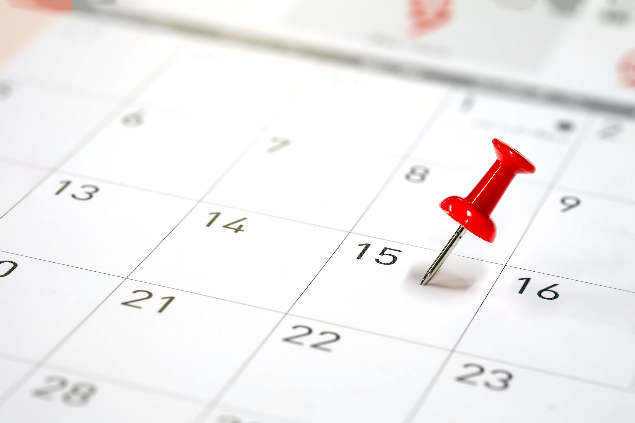 Kalender, in den ein roter Reißnagel auf ein bestimmtes Datum gesteckt ist